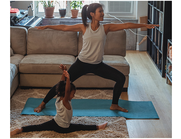 adulte et enfant pratiquant le yoga dans un salon